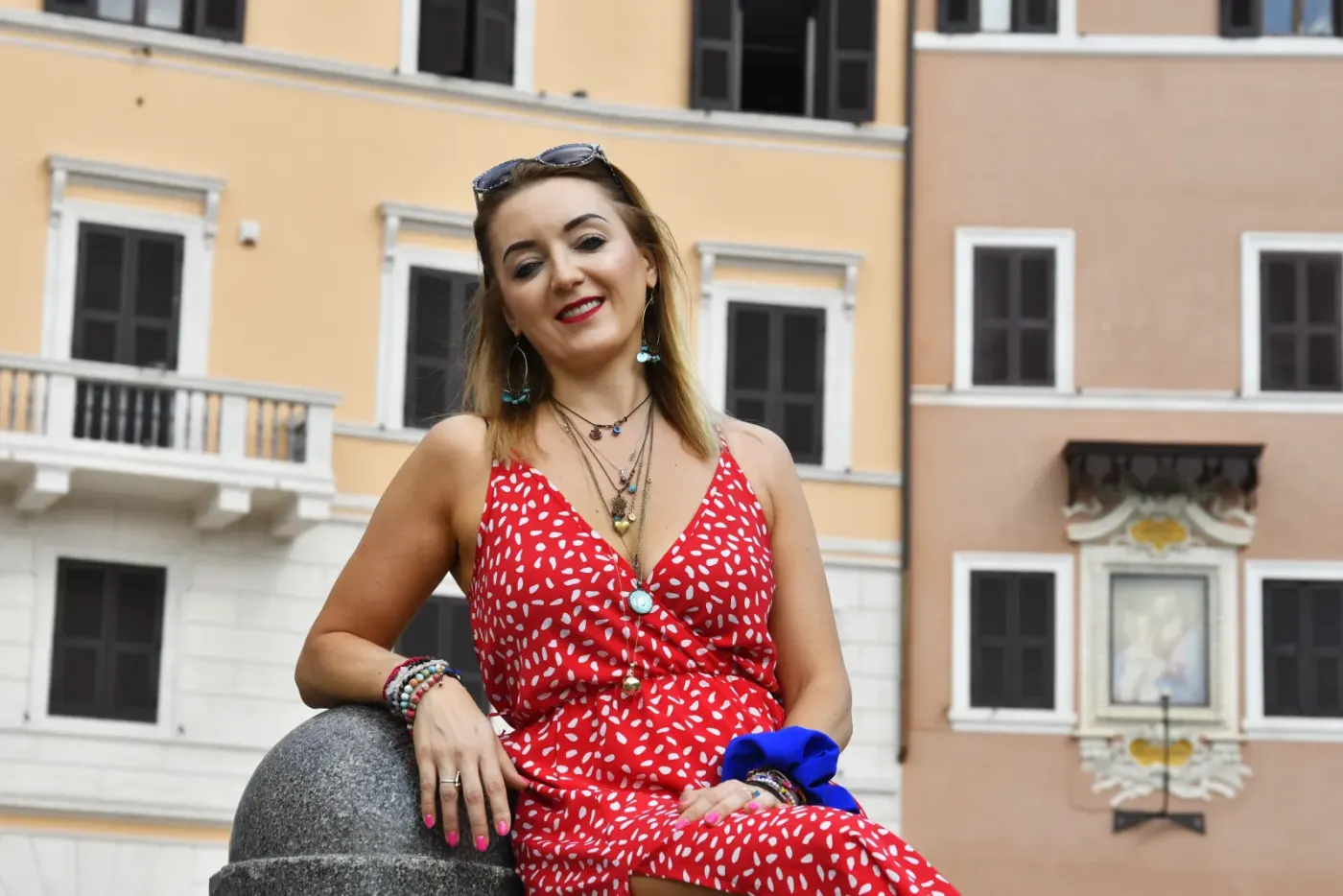 Agnieszka Piaseczna w czerwonej sukience na tle kamienicy